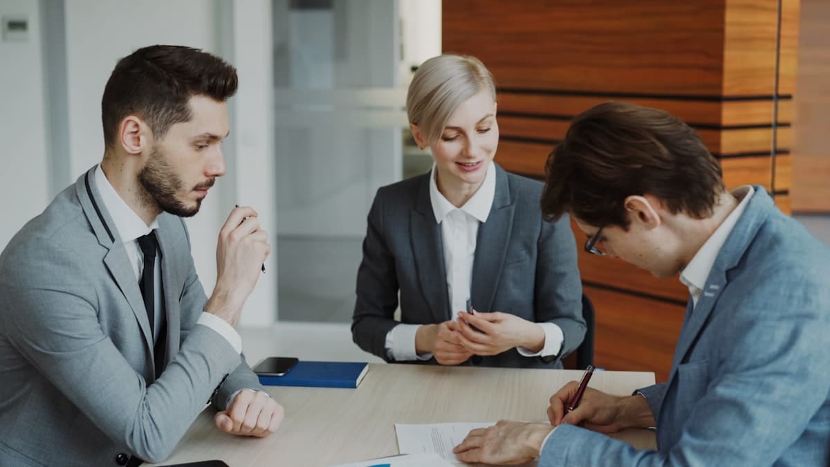 Business professionals signing a loan agreement at a meeting table